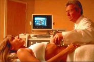photo of a pregnant woman undergoing ultrasound monitoring of her fetus in a doctor's office