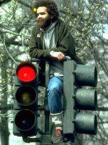 Photo of a man sitting on top of a corner traffic light
