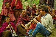 photo of a North American man playing a Tibetan horn with monks in a monestery