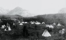 photo of a 19th century Indian camp with numerous tipis in the foothills of the Rocky Mountains