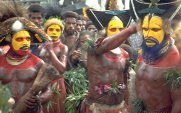 Photo of a group of Papua New Guinea men with brightly painted bodies arranging their head ornaments in preparation for a ceremony