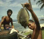 photo of two Polynesian teenagers with a fish that they speared