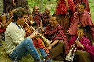 photo of a North American ethnographer playing a Tibetan horn with monks in a monastery