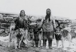 19th century photo of a Canadian Inuit man and woman with some of their dogs
