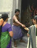 photo of a Hindu priest and two women at the entrance to a Hindu temple