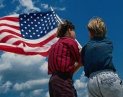 photo of two kids standing in front of an American flag