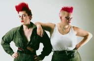 photo of two defiantly posing young women with atypical hair styles and blood red dyed hair