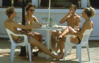 photo of 4 young adults in swim suits casually talking together over drinks