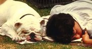 photo of a woman and her dog sleeping next to each other on the grass in a park
