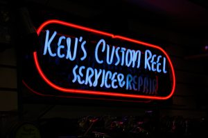 Neon sign reading "Ken's Custom Reel, Service & Repair."